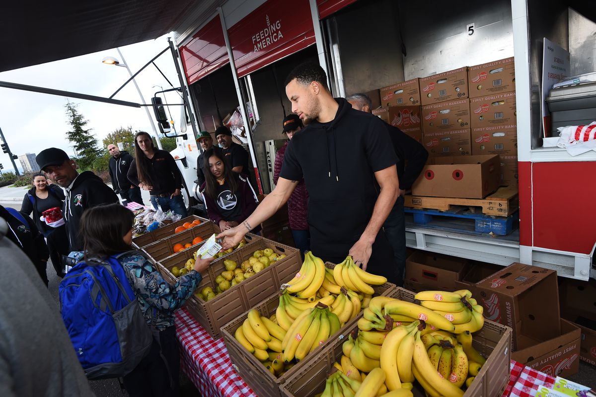 Steph Curry handing out food to unhoused people at an event